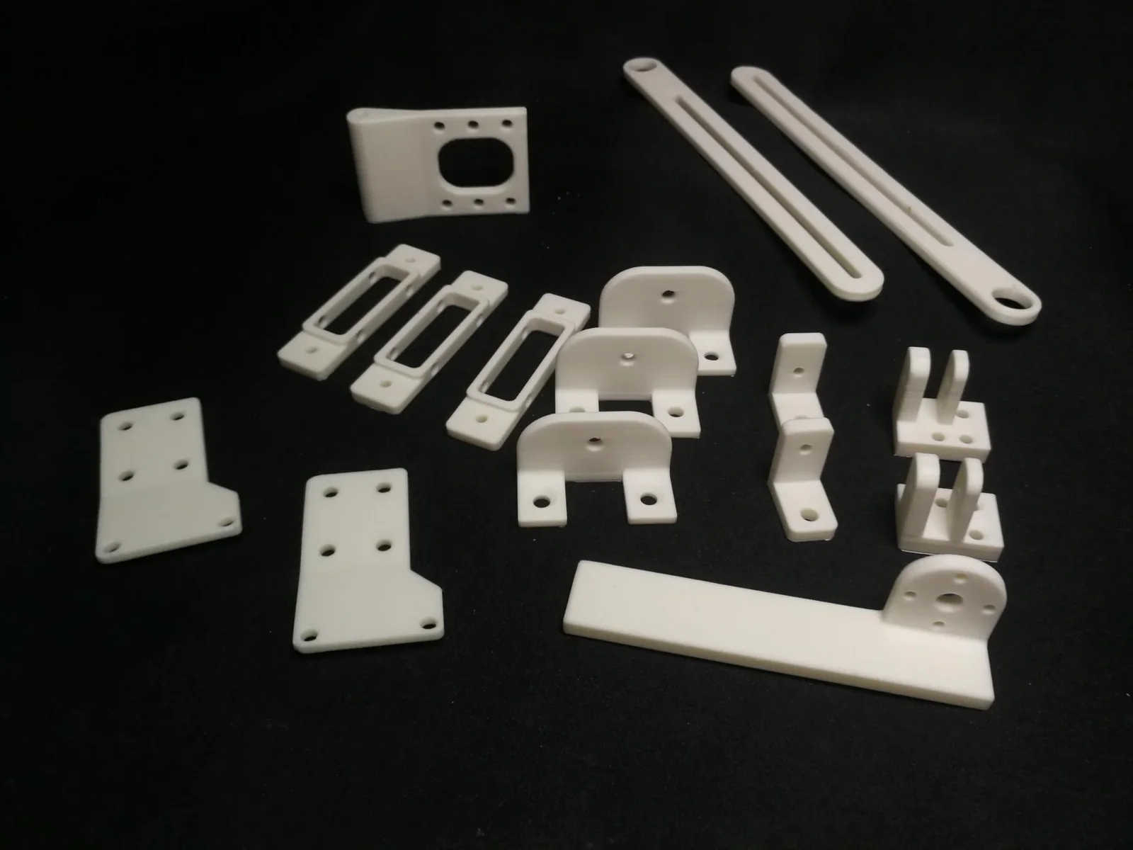 3D-printed brackets and mechanical parts for robots, on a black surface