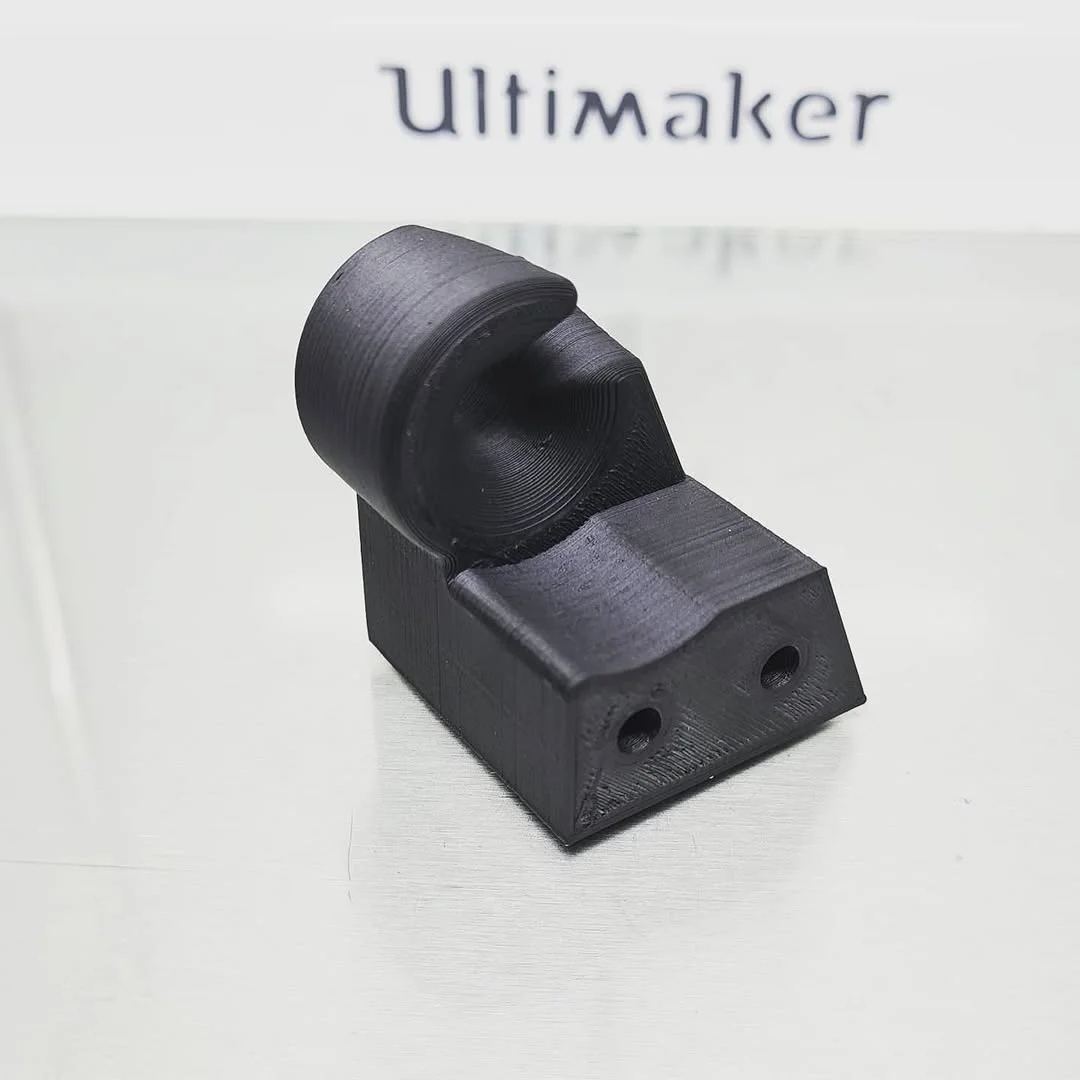 Crni 3D štampani prototip od ESD-PPS filamenta, ispred natpisa Ultimaker