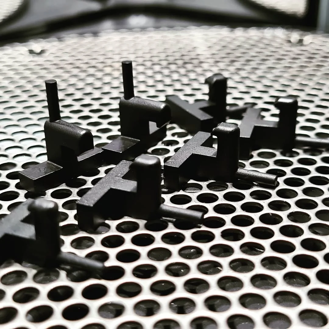 Black spare parts printed with SLA technology, arranged on a perforated metal plate